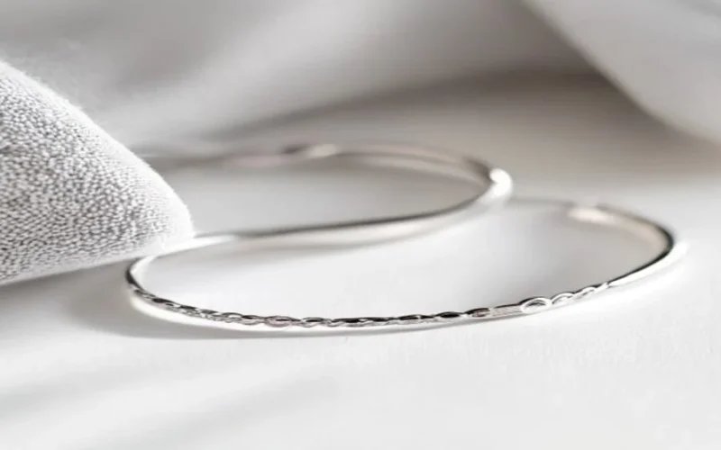 A delicate silver bracelet being wiped with a soft microfibre cloth