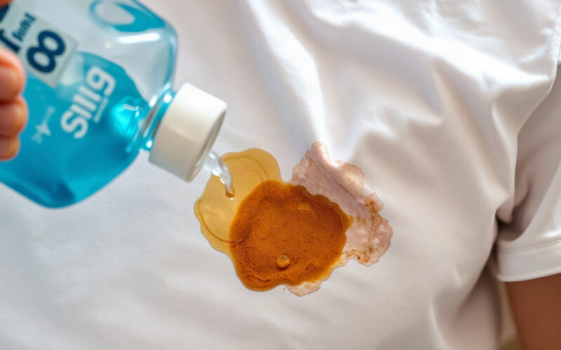 Dish soap being worked into an oil stain on a white cotton t-shirt